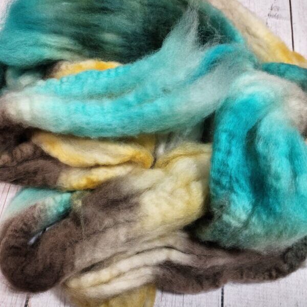 20230224_232823 A pile of Disco Date ~ 100g Hand-Dyed Luxury Combed Top Fiber on a wooden floor.