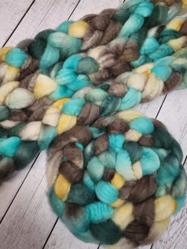 A skein of Disco Date ~ 100g Hand-Dyed Luxury Combed Top Fiber and a ball of Disco Date ~ 100g Hand-Dyed Luxury Combed Top Fiber.